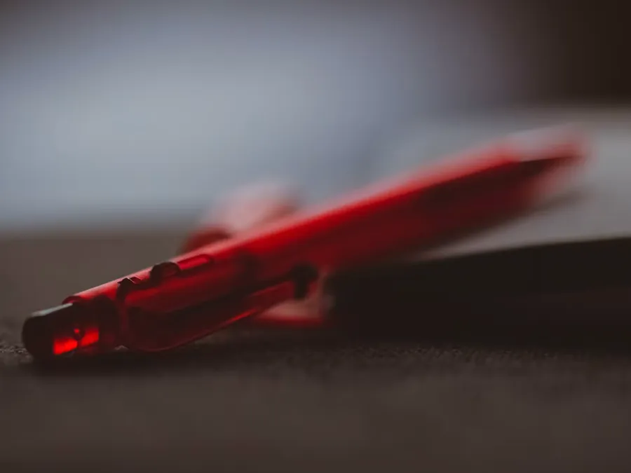 A red pen resting on a marked-up page